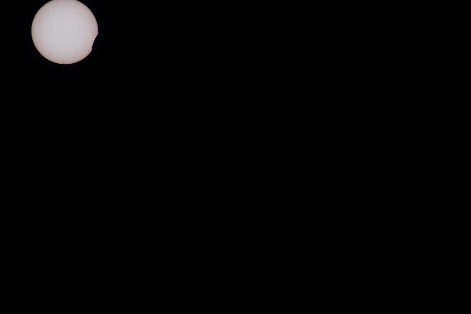 Beginn der Sonnenfinsternis am Himmel über der Hornisgrinde im Schwarzwald, bei der der Mond einen Teil der Sonnenscheibe verdeckt.