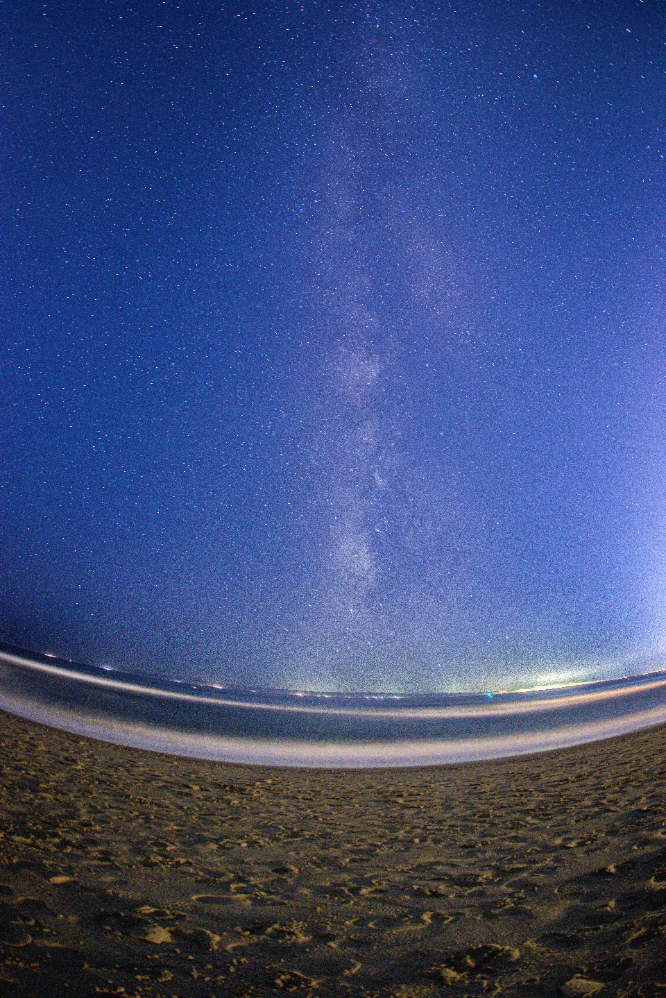 Sternenhimmel mit sichtbarer Milchstraße über dem dunklen Strand von Marbella an der Costa del Sol in Spanien.